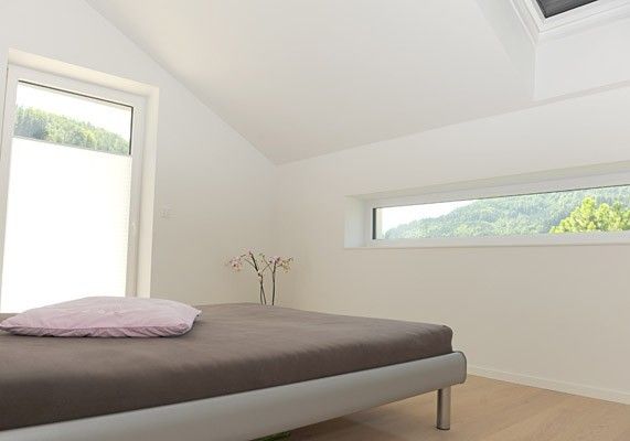 Modern eingerichtetes Schlafzimmer mit großen Fenstern und Blick in die Natur.